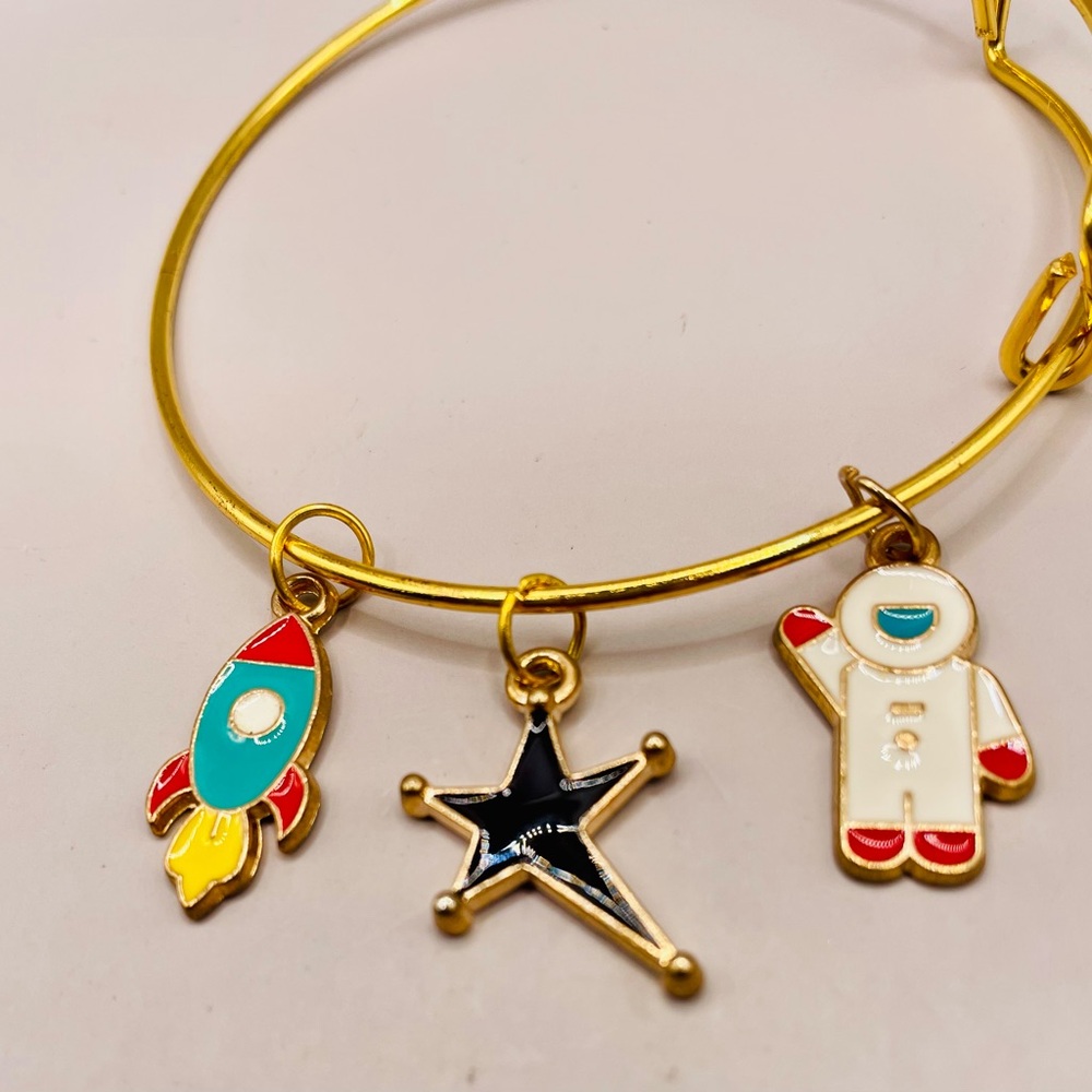Gold tone bangle charm bracelet. Space rocket, star, and astronaut enamel charms